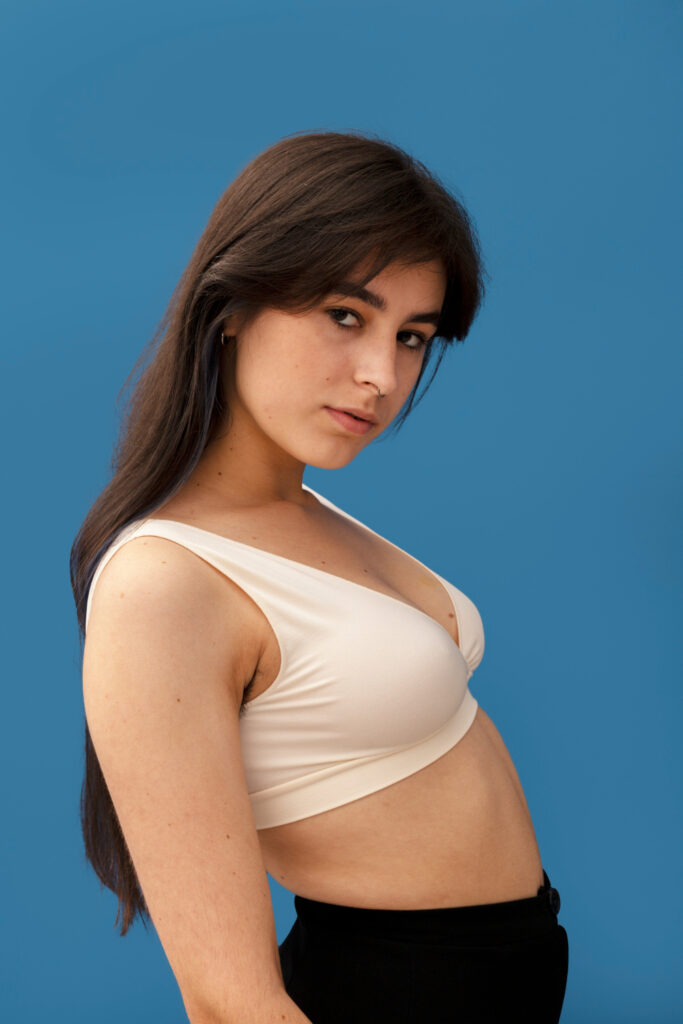 Mujer joven de perfil con top ajustado mostrando el contorno del pecho, imagen vinculada a cirugía mamaria estética