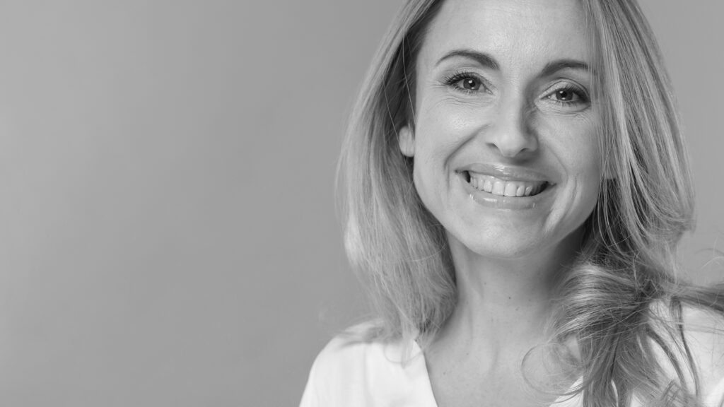 Imagen artística en blanco y negro de mujer madura sonriente con rasgos faciales naturales y cuello definido, vinculada a lifting de cara y cuello